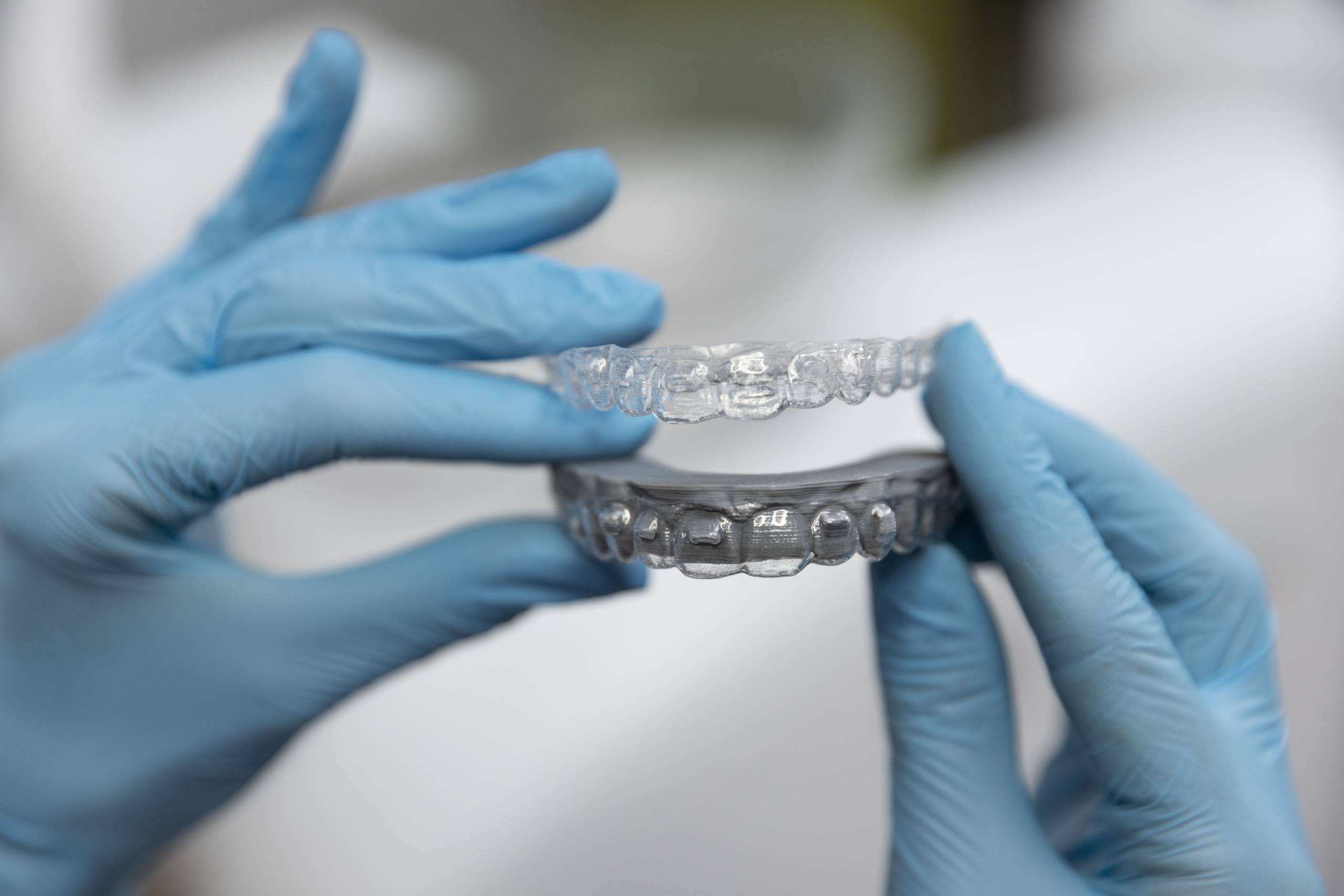Orthodontist holding clear invisible braces aligners used for correcting overbite, crowded teeth, and gaps between teeth.